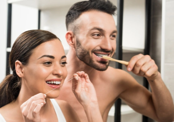 A couple brushing and flossing their teeth