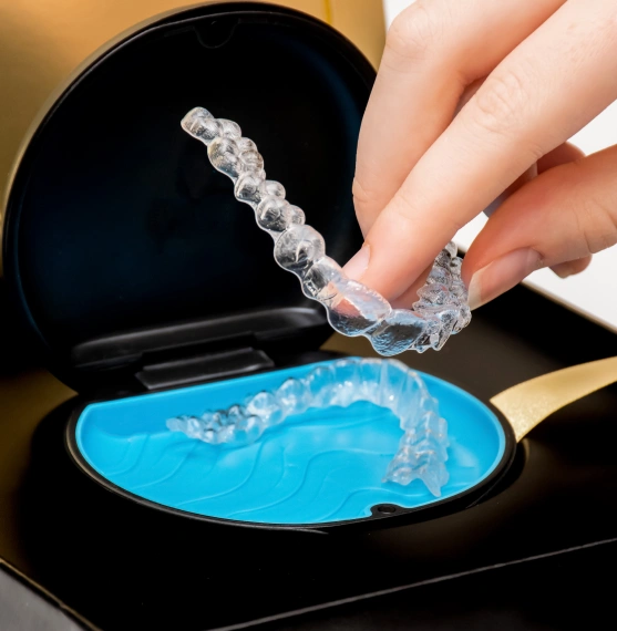 Close up of a hand holding an invisalign aligner
