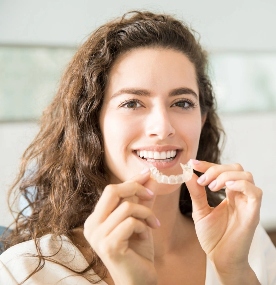A woman holding an invisalign aligner near her mouth