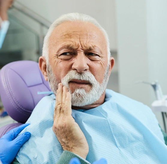 An older man touching his jaw in pain